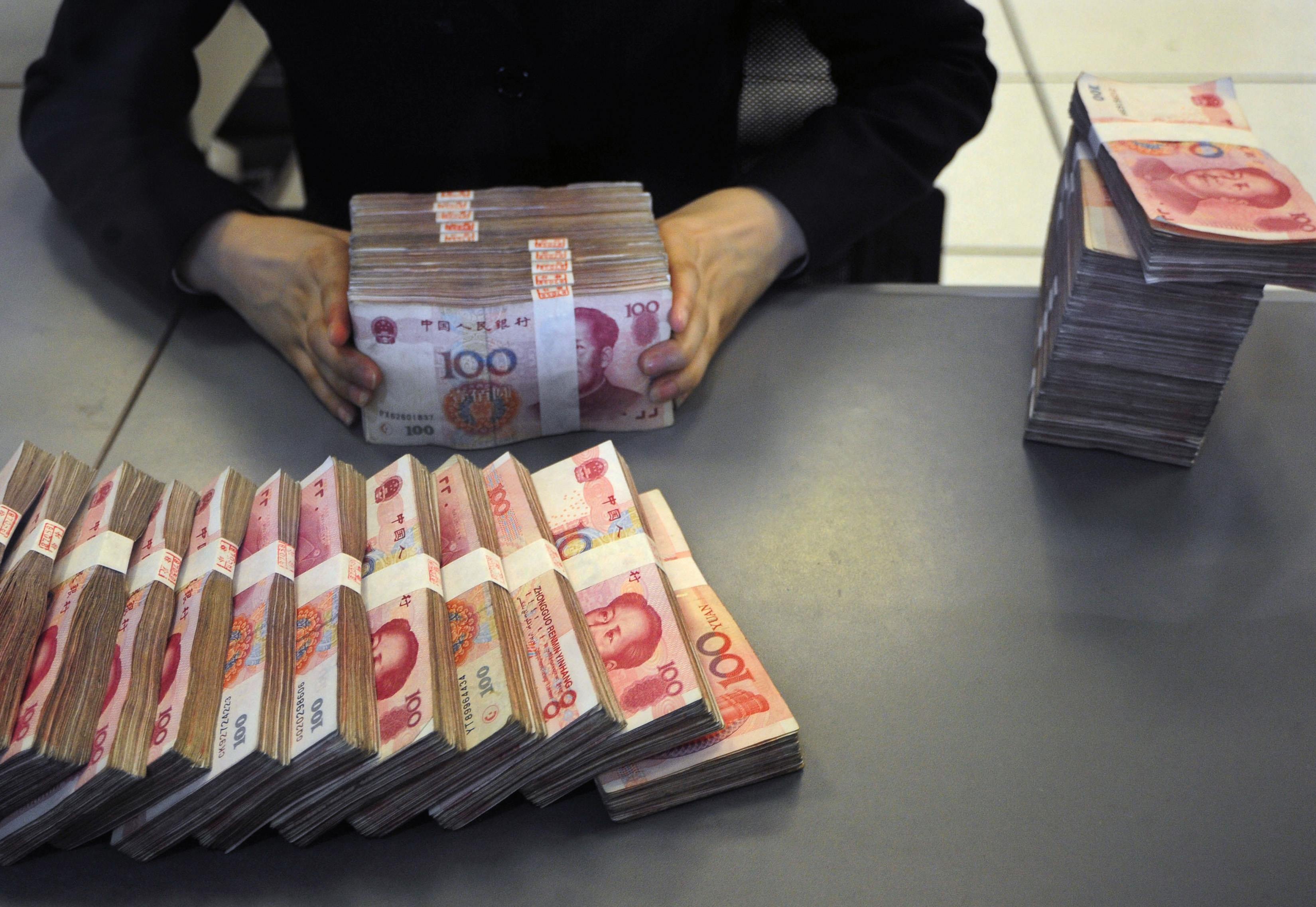 An employee counts yuan banknotes at a branch of the Pudong Development Bank in Hefei